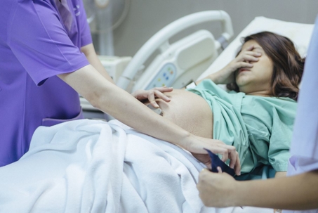 Scared pregnant woman in hospital examined by nurse