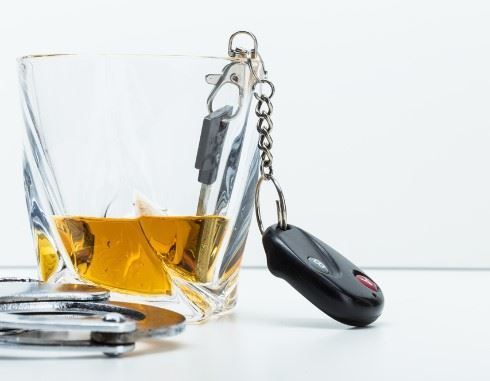 glass of alcohol with car keys next to it